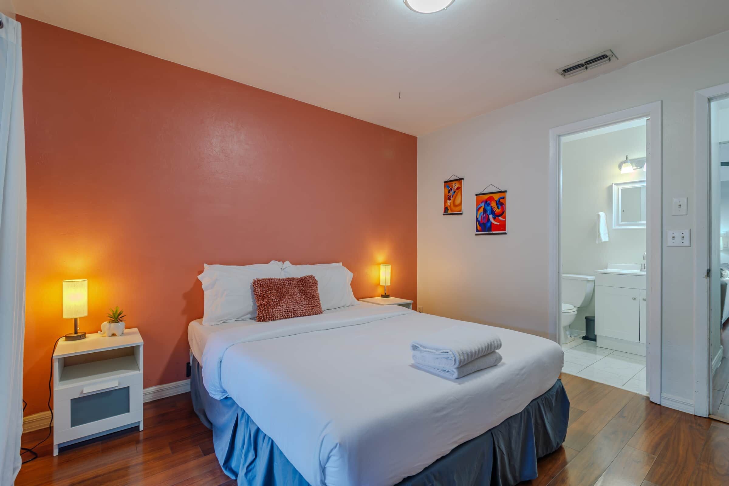 Une chambre à coucher avec un lit, des tables de chevet, une lampe et un tableau au mur.