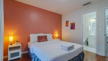 Une chambre à coucher avec un lit, des tables de chevet, une lampe et un tableau au mur.