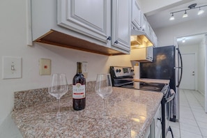 A kitchen with granite countertops, a wine bottle, and glasses. - Gainesville Fur Friendly Condo (Gainesville)