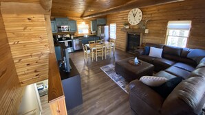 Ein Holzblockhaus-Innenraum mit Wohnzimmer, Essbereich und Küche.