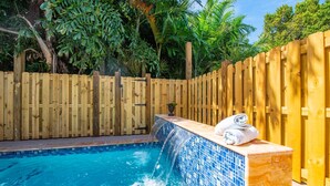 A swimming pool with a wooden fence, a tiled edge, and a towel on the edge.