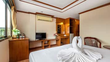 A hotel room with a bed, a desk, a television, a mirror, and a window with curtains.