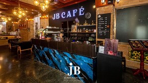 Un JBCafé con mostrador negro, cartel de menú y zona de bar.