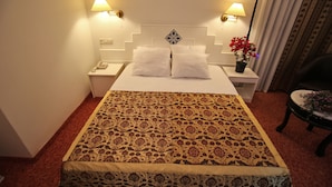 Une chambre d’hôtel avec un grand lit, deux lampes de chevet, une table de chevet, une chaise et une plante en pot.