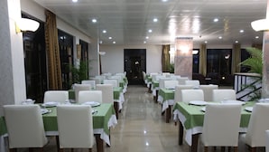 Un espace repas avec des tables dressées, agrémenté de nappes vertes et de chaises blanches.