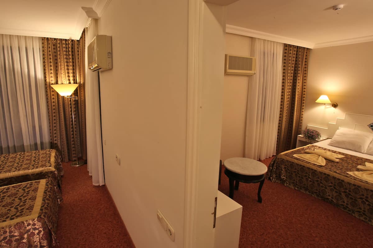 A hotel room with two beds, a sitting area, a desk, and a bathroom.