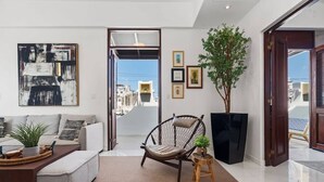 A modern living room with a sofa, a wicker chair, a coffee table, and a potted plant.