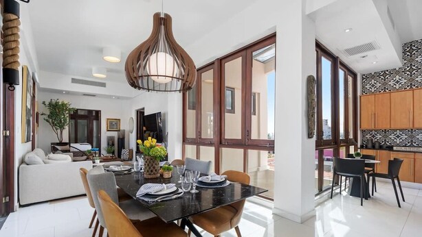 A modern dining area with a black table, brown chairs, and a hanging light fixture.