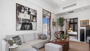 A modern living room with a grey sofa, a coffee table, and a large abstract painting on the wall.