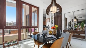 A dining area with a black table, wooden chairs, and a large window with a city view.