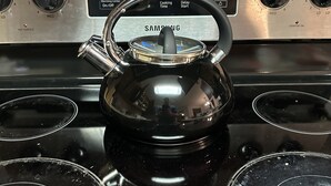 A black electric kettle on a stainless steel stovetop with four burners, a digital control panel, and a visible brand name. - Quiet and Cozy Home in the Heart of Southaven (Southaven)