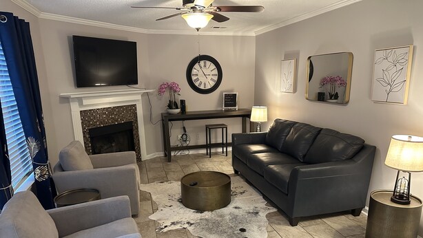 A living room with a fireplace, a sofa, a coffee table, a TV, and a clock. - Quiet and Cozy Home in the Heart of Southaven (Southaven)