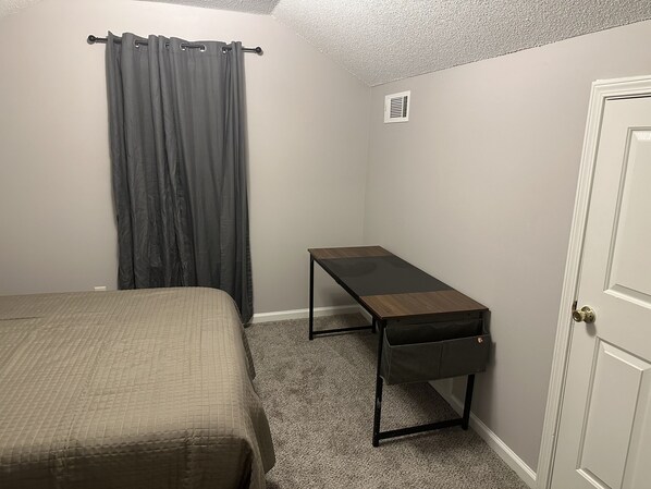 Een slaapkamer met een bed, een bureau en een deur.