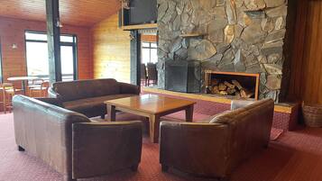 A cozy interior with a stone fireplace, leather sofas, and a wooden coffee table.
