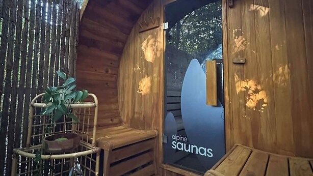 A wooden sauna with a glass door, a wooden bench, and a bamboo plant. - Lakes Lodge Okataina (Lake Okataina)