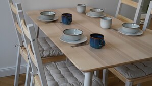 A dining table with multiple bowls and cups, surrounded by chairs with cushions. - Helle und Klare Fewo in Altstadtvilla (Quedlinburg)
