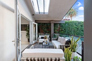 A balcony with a sofa, a table, and potted plants. - Cozy LA Living West Hollywood Home (Los Angeles)