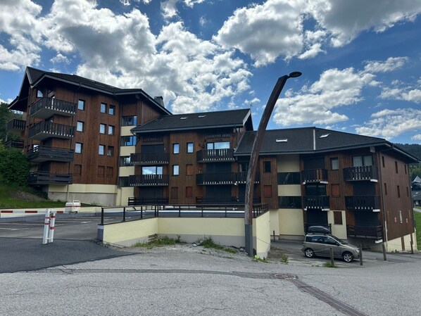 A multi-story building with balconies, a parking area, and a street lamp. - Comfortable apt. for 6 on ski slopes in Morillon (Morillon 1100)