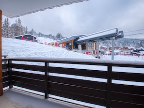A ski resort with a wooden fence, snow-covered buildings, and a ski lift.
