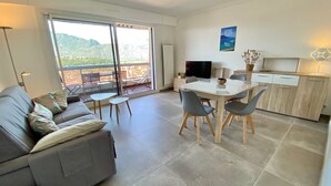 Una sala moderna con un sofá, una mesa de comedor con sillas, un televisor y una cocina con armarios.