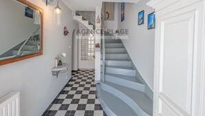 A hallway with a checkered floor, a white staircase, a mirror, a sink, and a radiator.