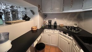 A kitchen with white cabinets, a black countertop, a coffee maker, and a trash can.