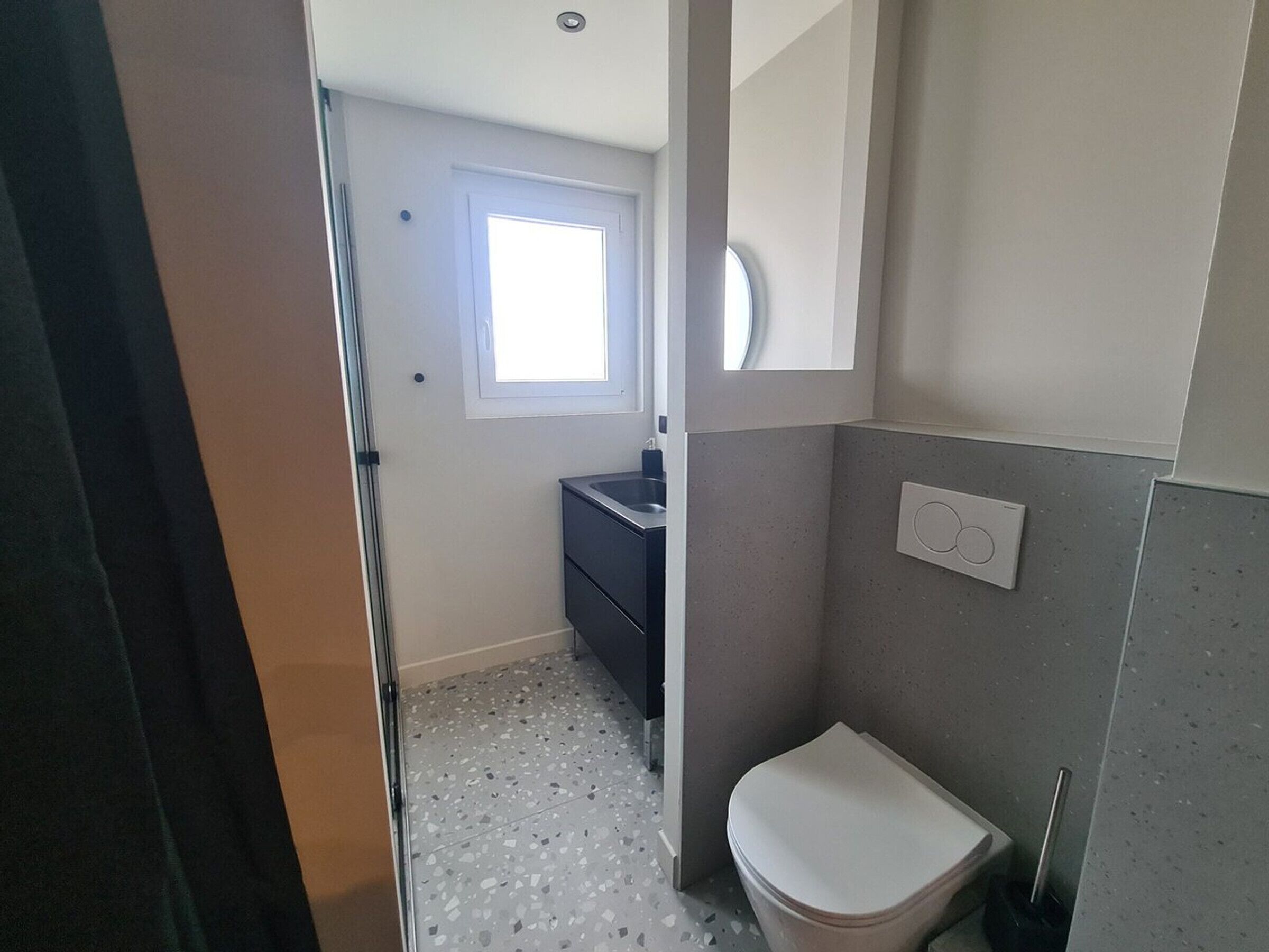 A small bathroom with a toilet, a sink, and a mirror.
