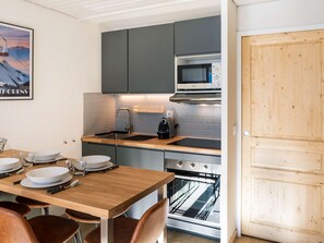 Uma cozinha compacta com armários cinza, micro-ondas embutido, cafeteira e forno duplo.