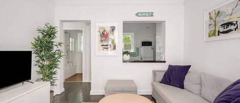 A modern living room with a flat-screen TV, a sofa, a coffee table, and a potted plant.