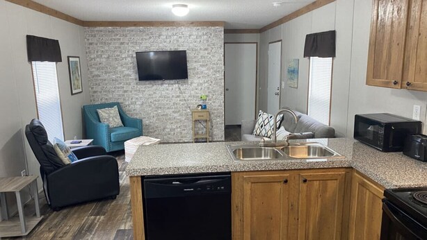 A compact kitchen with a dishwasher, microwave, and wooden cabinets. - Rainbow River Bungalow Q (Dunnellon)