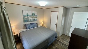 A bedroom with a bed, a painting, a door, and a desk. - Rainbow River Bungalow Q (Dunnellon)