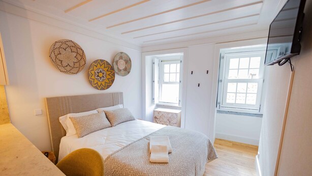Een slaapkamer met een bed, een stoel, een raam en decoratieve wandplaten.
