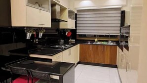Cozinha moderna com bancada preta, armários de madeira e área de refeições com mesa e cadeiras.