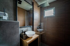 Une salle de bain moderne avec un meuble-lavabo en bois, un grand miroir, un lavabo blanc et un espace douche.