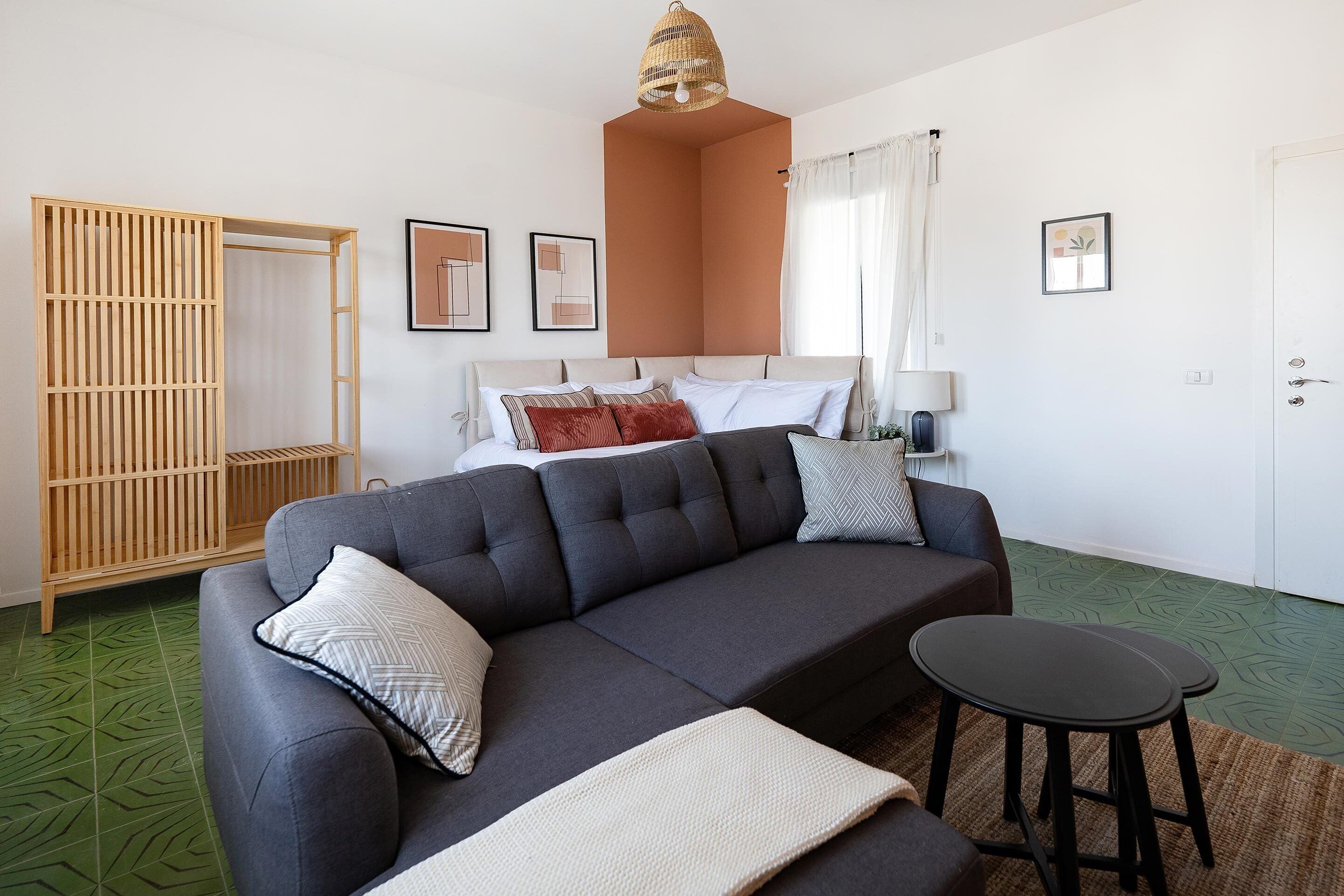 A modern living room with a grey sofa, a small round table, and a wooden wardrobe.