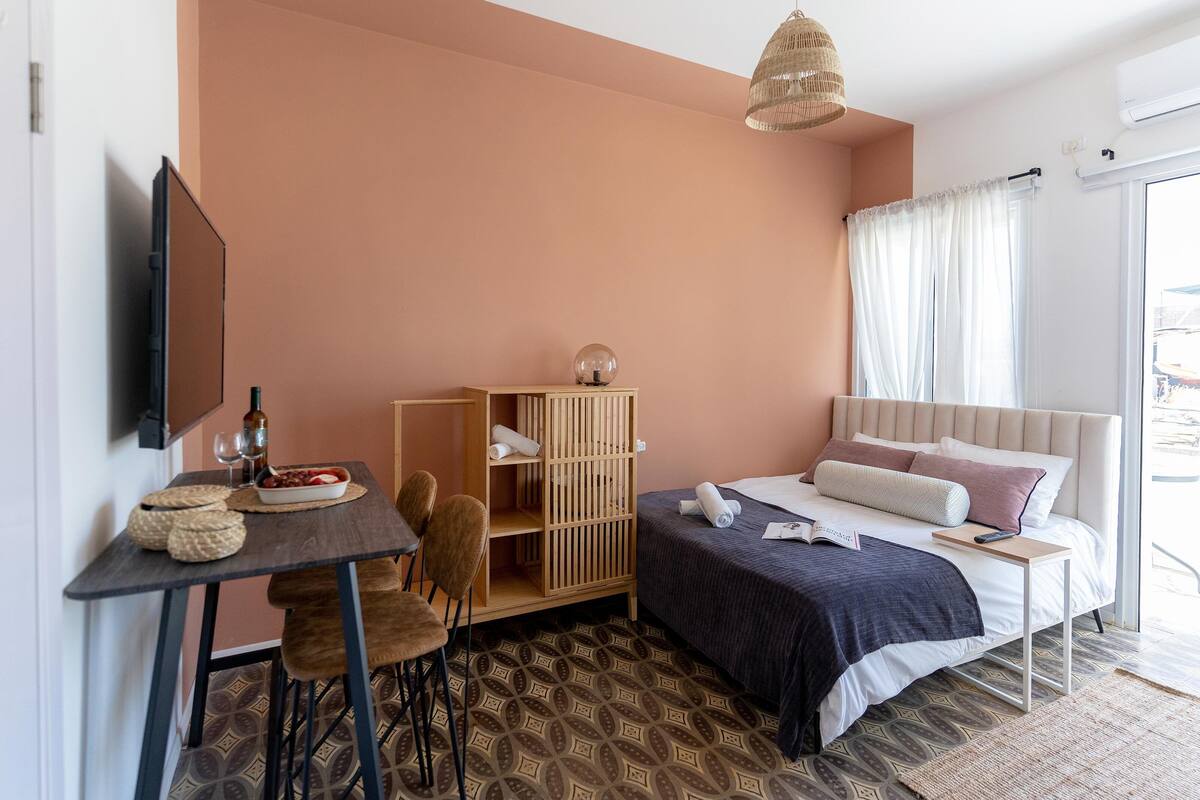 Une chambre à coucher comprenant un lit, un bureau, une chaise, une armoire et un luminaire suspendu.