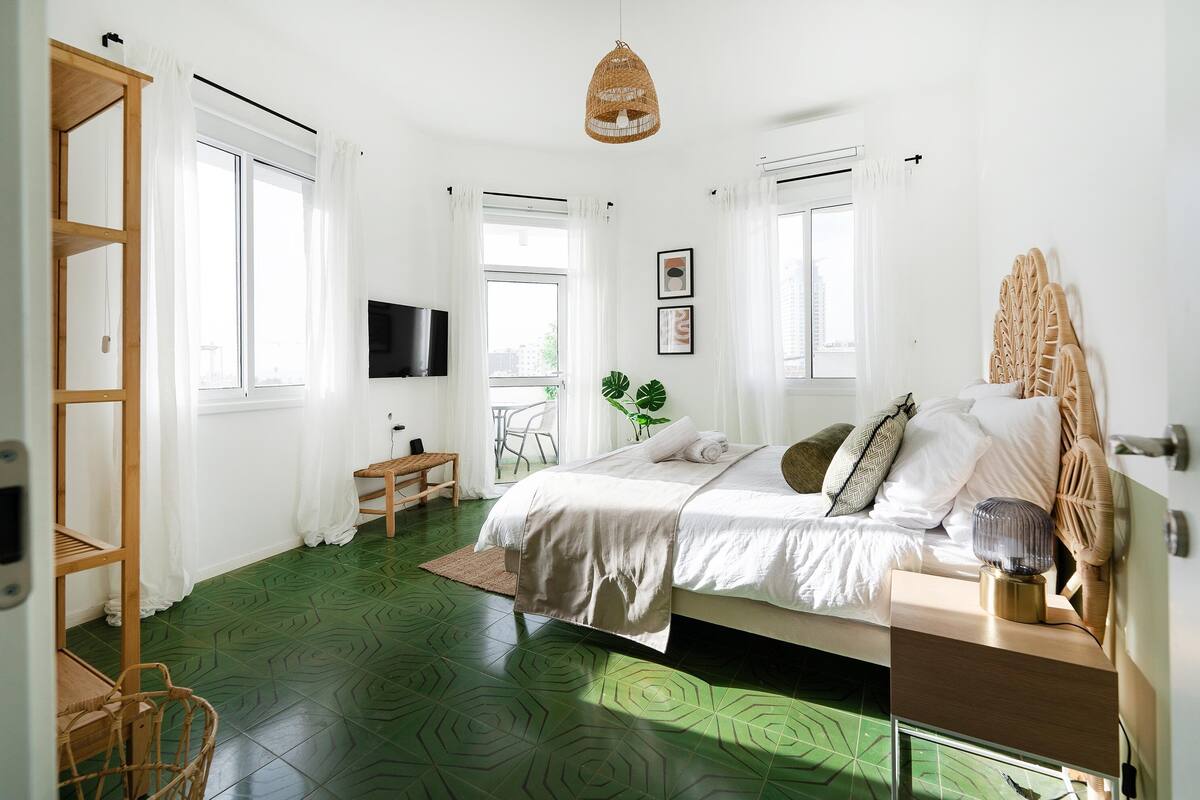 Une chambre à coucher avec un lit, une table de chevet, une télévision, une chaise et une fenêtre.