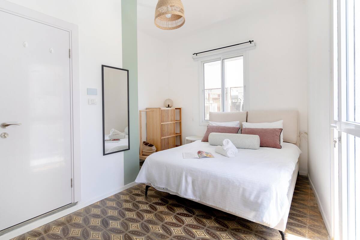 Une chambre à coucher comprenant un lit, une armoire, un miroir, une fenêtre et un luminaire suspendu.
