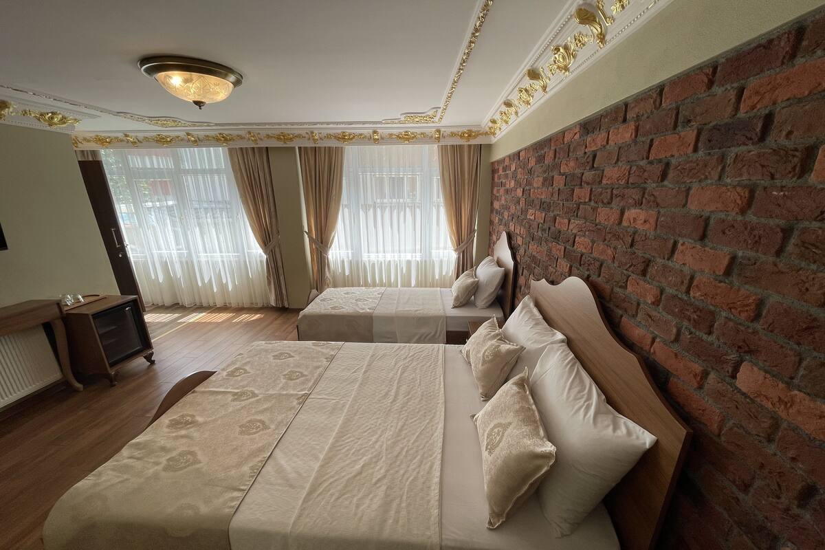 A hotel room with two beds, a brick wall, and a wooden floor.