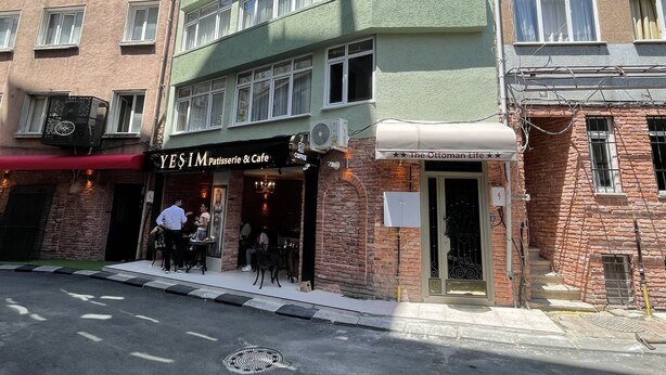 A multi-story building with a green facade and a coffee shop named 'YESIM Patisserie & Cafe' on the ground floor. - The Ottoman Life (Istanbul)