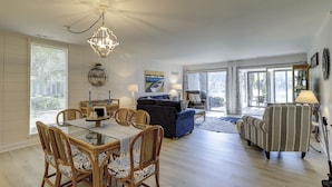 Ein geräumiges Wohnzimmer mit Essbereich, einer Kandelaberleuchte und Blick ins Freie.