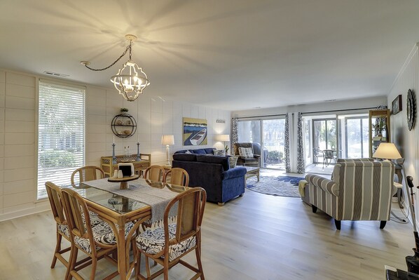 A spacious living room with a dining area, a chandelier, and a view to the outside. - 2 BR Lagoon & Golf Views Walk to Ocean King 2 Twins Bikes & Beach Gear included (Hilton Head Island)