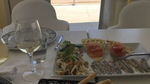 Ett matbord med en tallrik mat, ett glas vitt vin och en korg med grissinistänger.