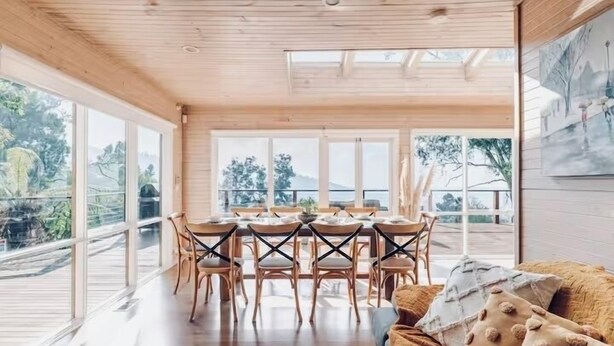A spacious dining area with a wooden table and chairs, large windows offering a view of the outdoors. - Villa with Spa and Breathtaking Views of Dandenong Ranges (Kalorama)