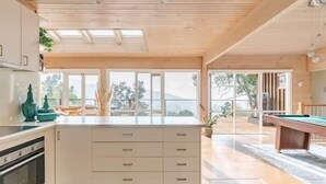 A modern kitchen with a central island, wooden ceiling, and large windows. - Villa with Spa and Breathtaking Views of Dandenong Ranges (Kalorama)