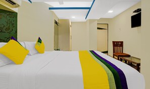 A hotel room with a bed, a chair, a TV, and a door. - Hotel Amber Corp Inn (Mumbai)