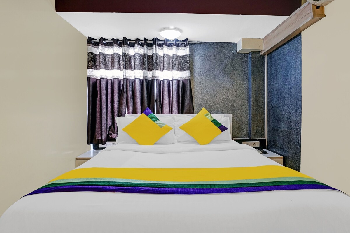 Una habitación de hotel con cama, cortinas, mesita de noche y una pared con textura.