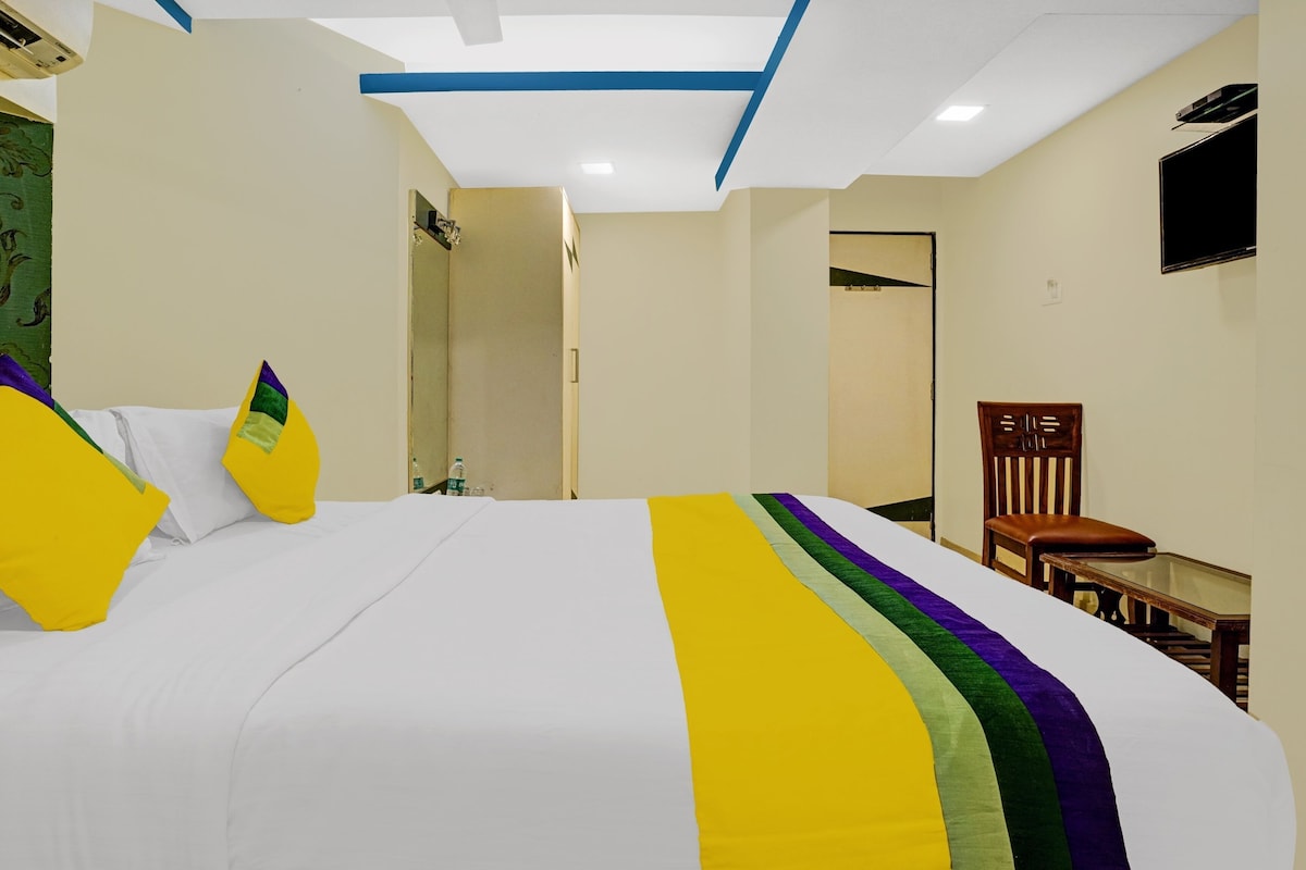 Una habitación de hotel con una cama, una silla, un televisor y una puerta.