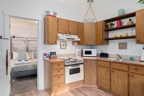 A compact kitchen with wooden cabinets, a stove, a microwave, and a sink. - Downtown Leavenworth King Suite #21 + parking (Leavenworth)