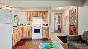 A compact kitchen with wooden cabinets, a white stove, and a microwave. - Downtown Leavenworth | King Bed + Parking (Leavenworth)